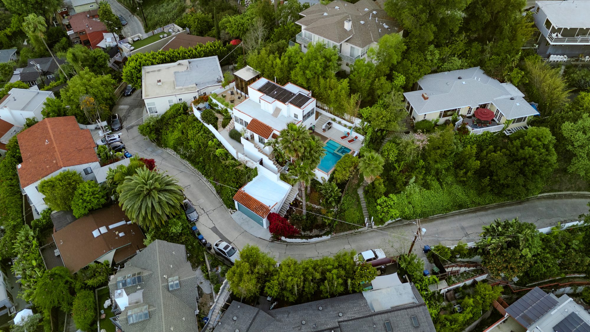 Aerial view of the house on its promontory where Dearborn Drive curves around it, showing the pool, studio, terraces, and neighboring houses