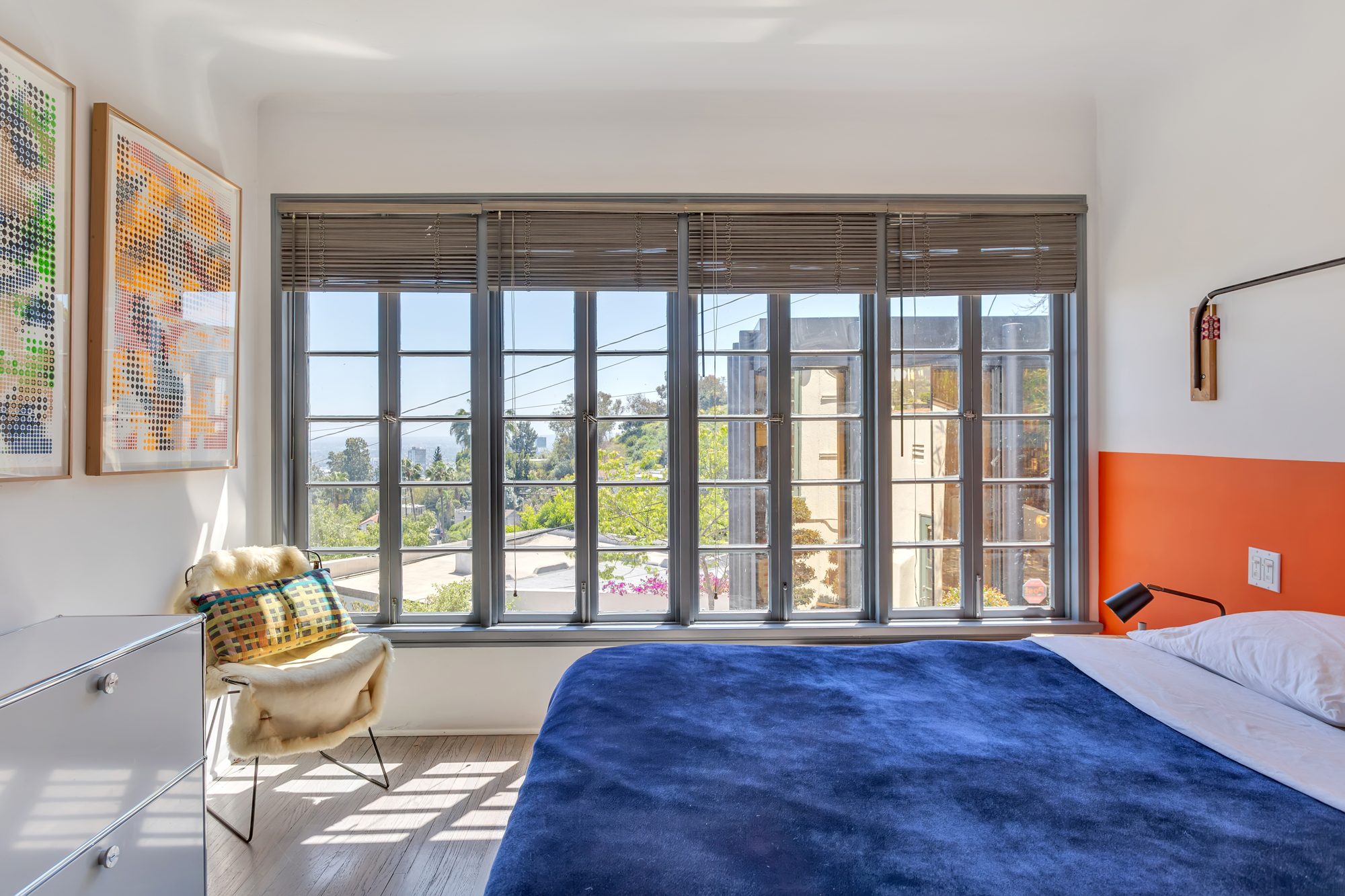 Larger bedroom with a wall of wood casement windows looking toward the studio and the city, hardwood floors