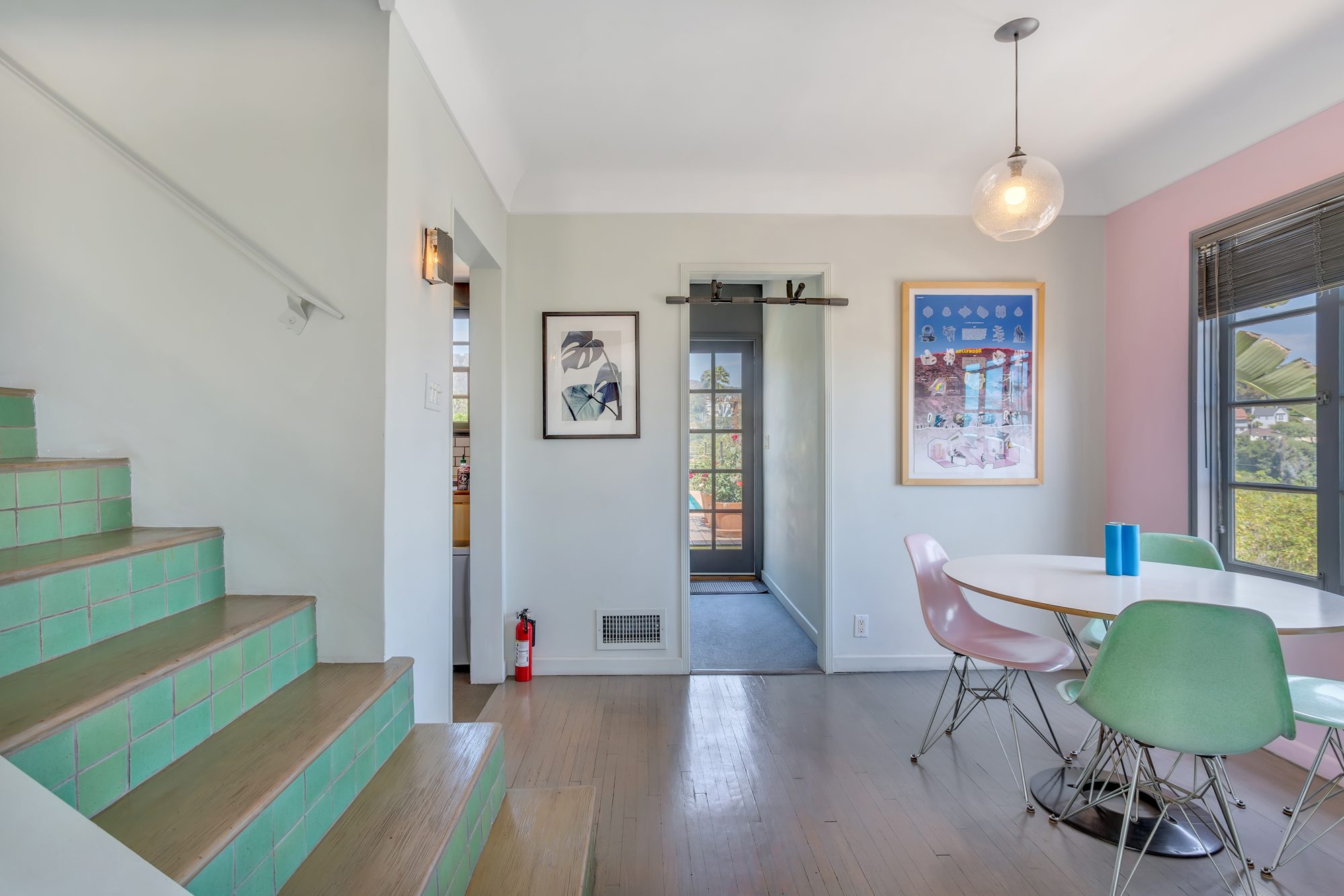 Dining area with hardwood floors, a pendant light, and a stair with original green tile risers leading to the bedroom level