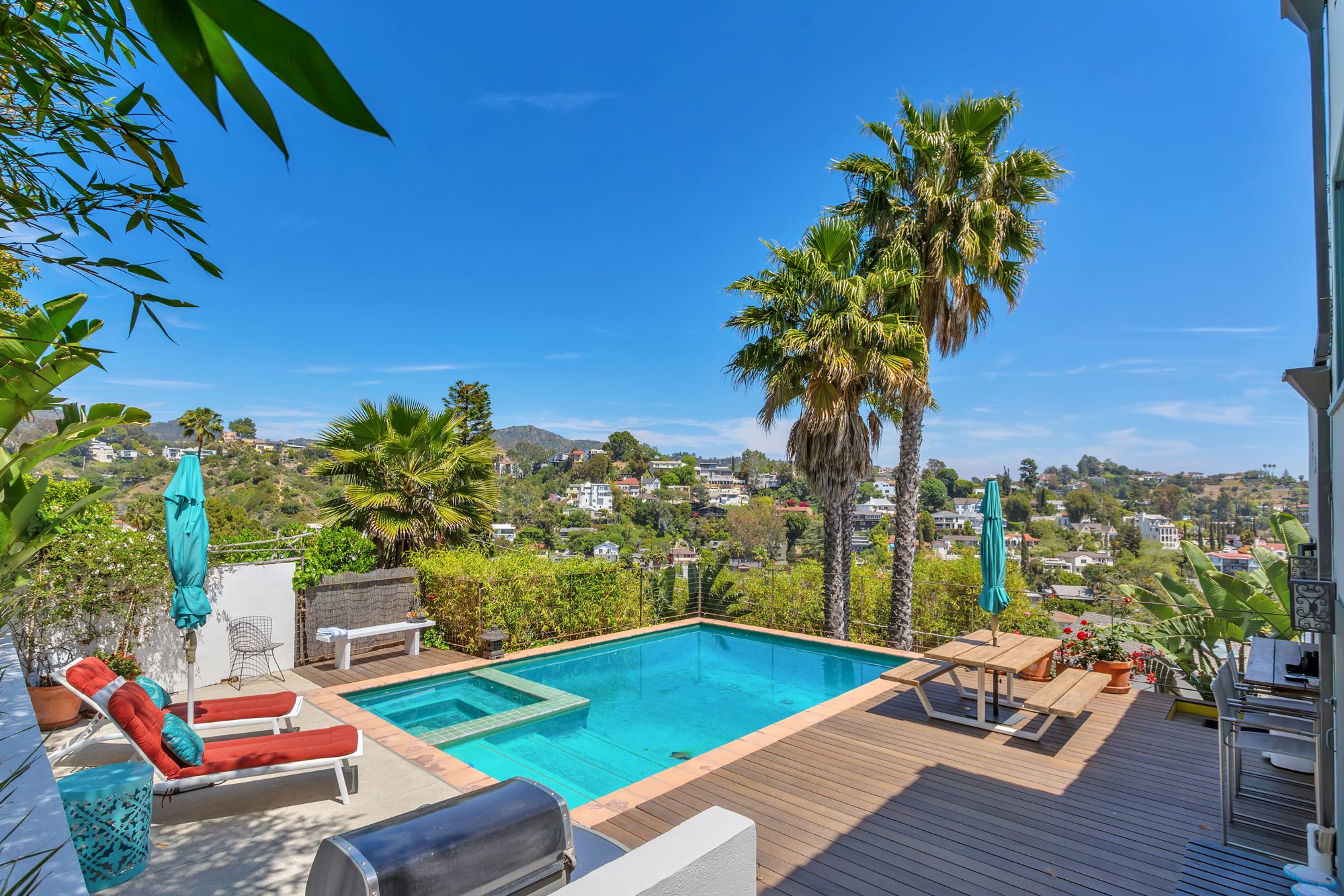 Pool and spa with a wood deck, lounge chairs, picnic table and built-in barbecue, looking across Beachwood Canyon
